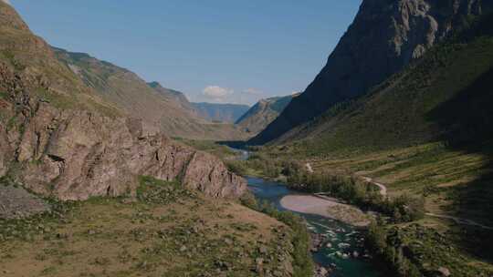 阿尔泰绿色田野和蓝色晴朗天空的山脉之间的Chulyshman河