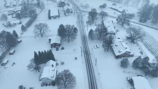 空中鸟瞰在美国白雪覆盖的村庄上空拍摄。多