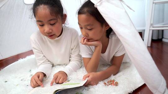 趴在帐篷里看书的两个女孩