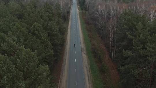 航拍在森林边的路上骑自行车