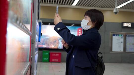 在地铁站内使用自动购物机的中国女性