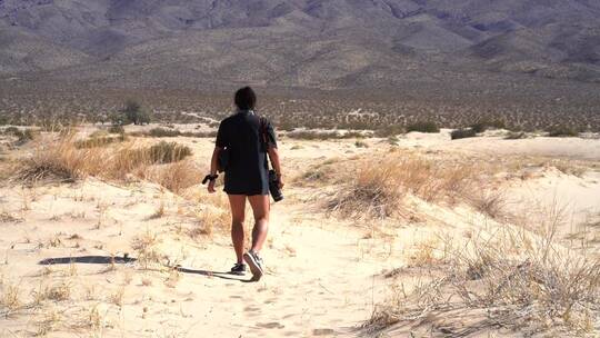 沙漠中行走的女摄影师视频素材模板下载