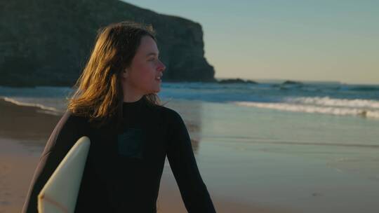 女孩拿着冲浪板行走在沙滩上视频素材模板下载