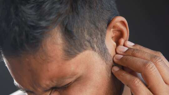 耳朵痛的年轻人触摸他疼痛的耳朵