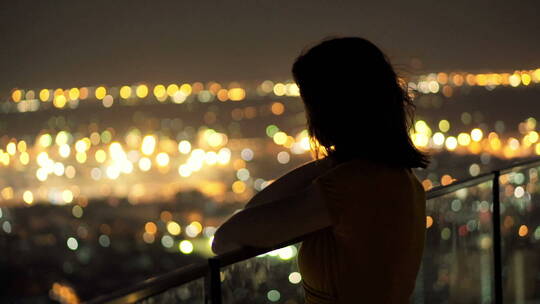女人在夜色中看着城市景观