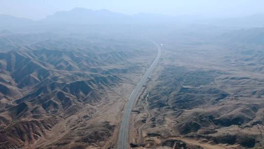 航拍两侧山峰环绕的荒野沙漠高速公路