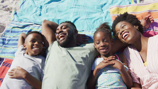 快乐的非裔美国家庭躺在海滩上大笑的视频