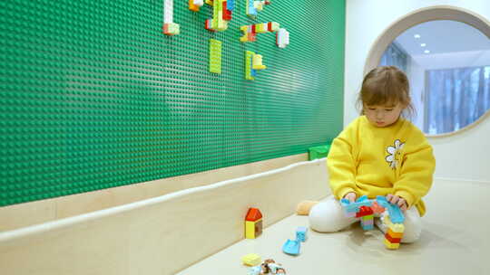 小女孩在室内游戏室玩彩色乐高积木——慢动视频素材模板下载