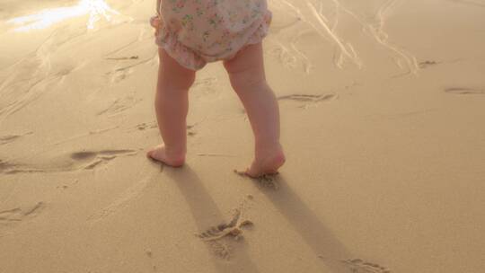 婴儿在沙滩蹒跚学步的腿部特写