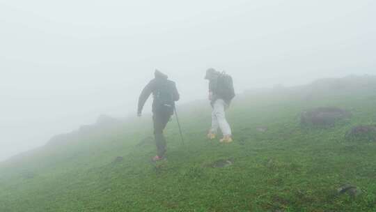 徒步攀登高山迷雾中行走团队战胜困难