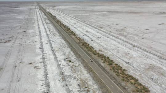 公路穿过新疆塔里木盆地荒芜的盐碱地