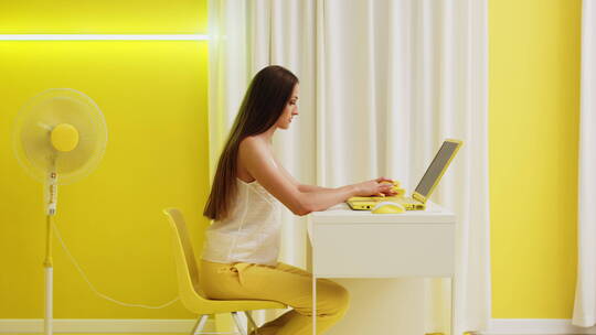 黄色背景下女人在用电脑