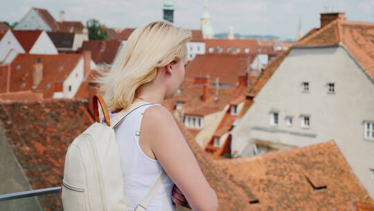 一位年轻的女游客站在高处欣赏这座古老的欧洲城市