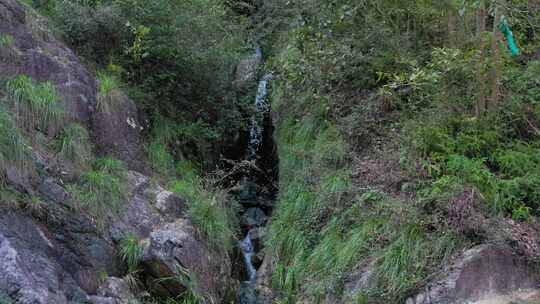 山间岩石缝中流淌着小溪的自然景观