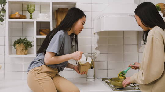 在厨房里煮食物和吃东西的女人