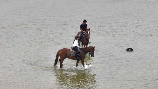 航拍俯瞰威海市环翠区金海路沙滩上的骑马人