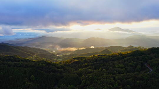 夕阳透过云层染红了山林