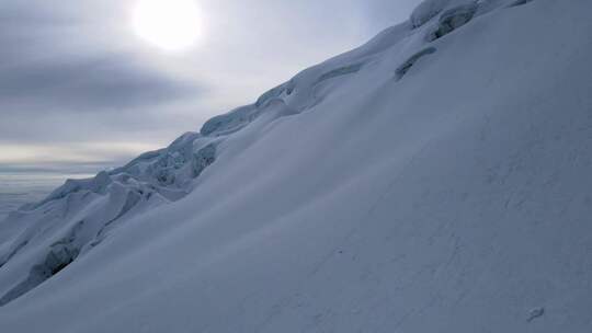 阳光照耀下的积雪覆盖的雪山坡