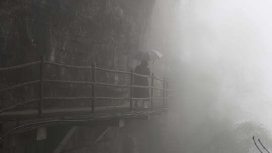 大雾笼罩的山上女生打着伞往前行走
