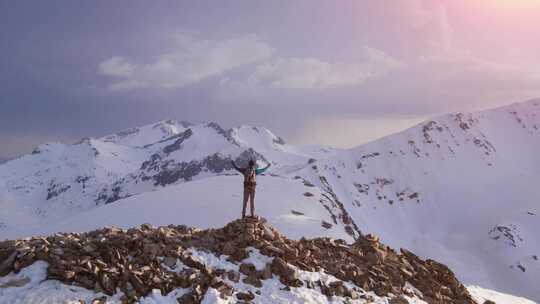 男人站在雪山顶张开双臂