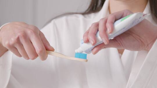 在牙刷上涂牙膏的女人