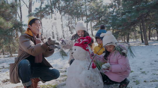 快乐家庭在雪地里堆雪人