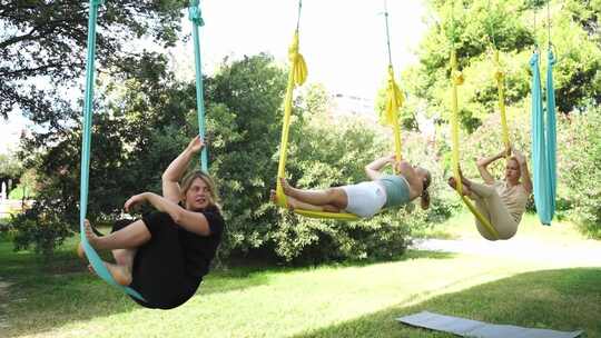 女性在公共公园户外一起锻炼瑜伽和吊床伸展