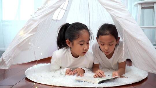 趴在帐篷里看书的两个女孩视频素材模板下载