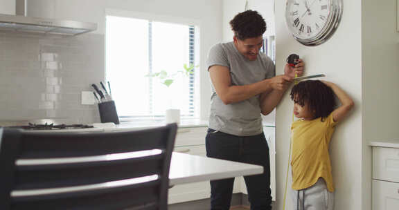 男人和他的儿子在厨房测量身高
