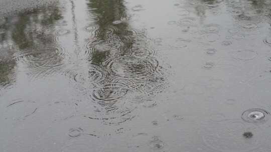 下雨天暴雨天雨滴落在马路积水上形成水坑