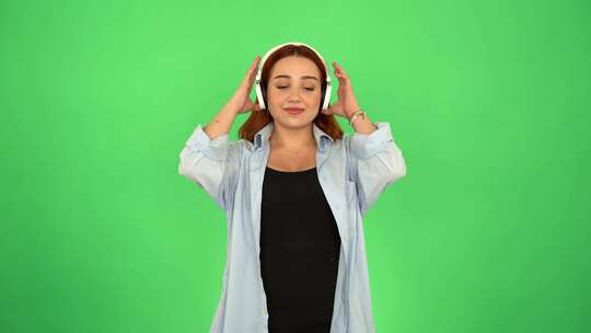 女人在绿屏上用耳机听音乐4K