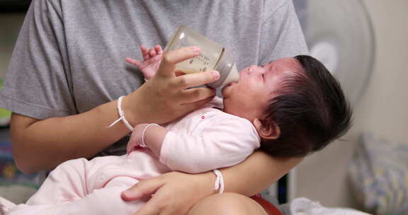 一位东南亚母亲用一瓶配方奶母乳喂养她的女