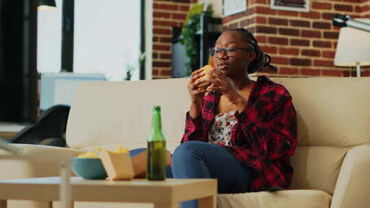 年轻女子吃芝士汉堡配薯条和啤酒