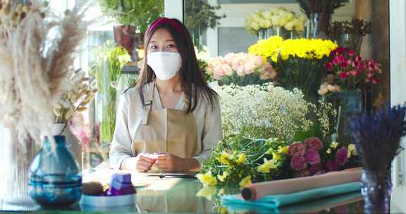 好看的亚洲女人戴着医用口罩在商店里卖花室