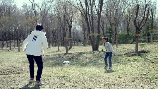 初春在公园草坪上踢足球的中国母女视频素材模板下载