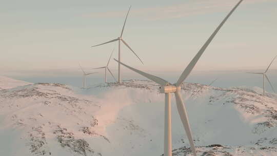 斯堪的纳维亚半岛雪山上旋转风力涡轮机的特写无人机视图