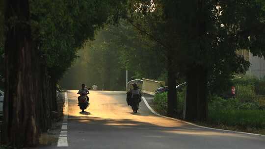 夕阳下的农村小路上骑电动车的村民素材