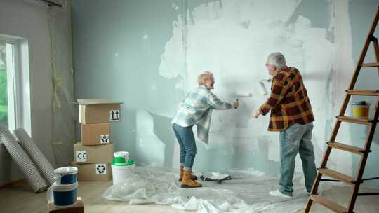两个老人正在粉刷墙壁