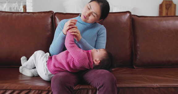 妈妈抱着宝宝在沙发上玩耍亲子欢乐温馨时光