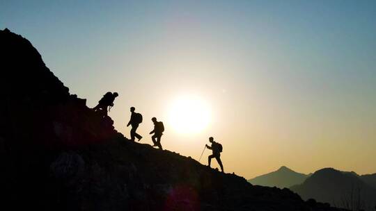 团队手拉手登山剪影攀登山峰团队精神登顶