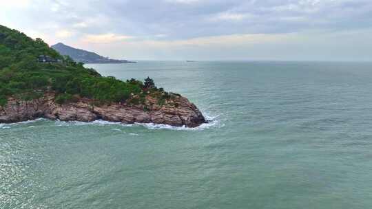 海岸边绿意盎然的山景与平静海面