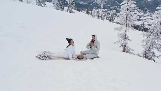 一个男人祈祷，而一个女人正在积雪覆盖的山