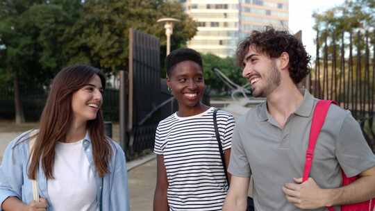 三个快乐的多种族年轻朋友在城市散步时闲逛