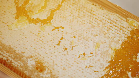 养蜂人用一把特殊的刀刮掉蜂蜜的表层