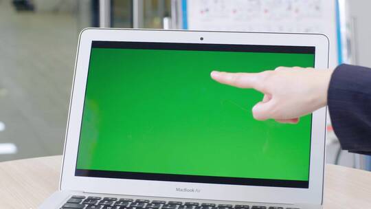 两只手指着绿屏笔记本电脑讨论工作