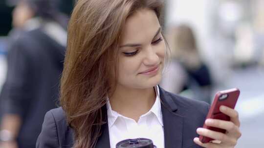 一名年轻女子用她的智能手机在城市街道上导