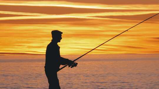 海上日落时拿着鱼竿的渔夫剪影