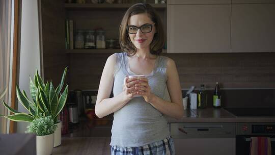 微笑的女人站在厨房拿着杯子
