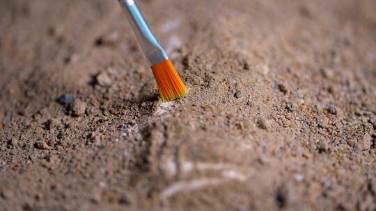 考古发掘人员用刷子轻轻扫去覆盖文物上沙泥视频素材模板下载