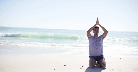 一个年轻的混血儿在阳光明媚的海滩上练习瑜